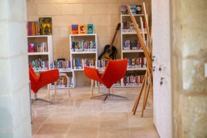 Biblioteca con sedie arancioni e chitarra